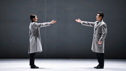 Two Performers in Grey Coats on Stage