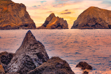 Scenic sunset view at Rodeo Beach in Marin Headlands, California. Dramatic sea stacks and ocean waves glowing in warm evening light, creating a peaceful coastal landscape along Highway 1
