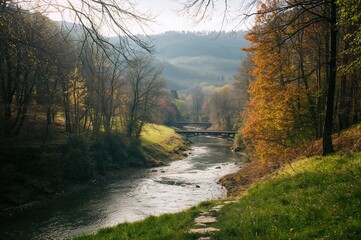 Obraz premium Early spring scenery of a river flowing through a lush valley filled with trees and grass