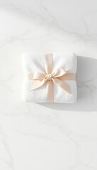 Fluffy white folded towels tied with a ribbon on a white marble surface presented as a clean and spa-like package