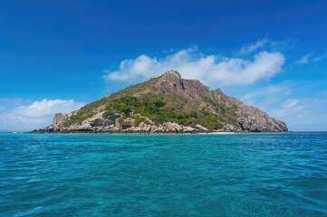 Fototapeta premium A solitary isle emerges from the deep blue sea, covered with lush greenery on rugged cliffs beneath a clear sky.