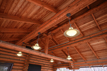 Exposed wooden beams and ceiling with warm pendant lights in a rustic log cabin interior