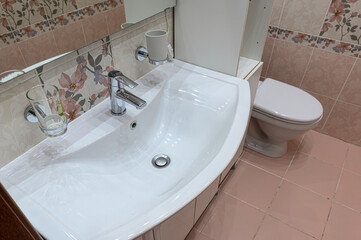 A clean bathroom sink with a chrome faucet and a toilet in the background