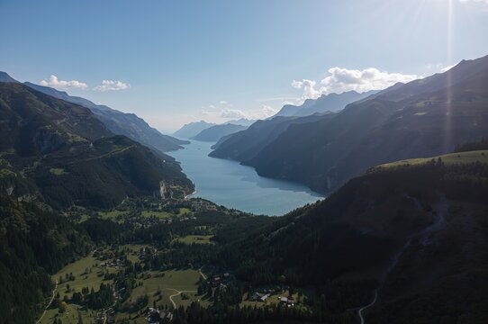 Bird's-eye perspective of a summer mountain valley featuring a lake and hiking trails captured by drone