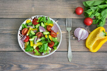 a vegetable salad with pepper, tomato, cucumber and lettuce with a fork