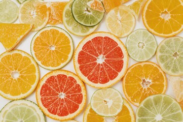 Obraz premium Assortment of citrus fruit segments displayed against a plain white backdrop. Includes lime, orange, lemon, and grapefruit.