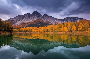 Obraz premium Thunderclouds loom over a majestic mountain range near a serene lake with vibrant autumn foliage reflecting on its calm surface.
