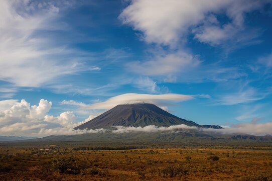 Volcanic mountain set against a bright sky with scattered clouds