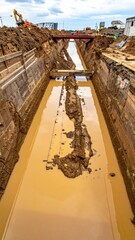 Obraz premium Construction Site Trench with Water Accumulation and Machinery