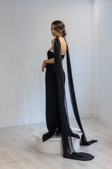 Fashion model in elegant black evening dress with dramatic cape detail posing
