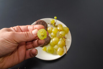 White grapes and chocolate biscuits on the same plate as two contrasts of healthy and unhealthy sugars and so-called treat foods on a dark background