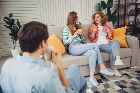 Group of young friends enjoying a casual conversation at home while sharing drinks in a relaxed living room setting