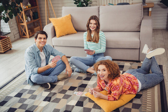 Young friends enjoying a card game with laughter and relaxation in a cozy modern home during the afternoon sunlight. - Powered by Adobe