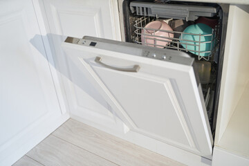Open dishwasher with clean dishes in a modern kitchen.