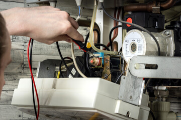 Maintenance of an electric water heating boiler; a man with a wrench and a spanner in his hands is repairing the boiler.
