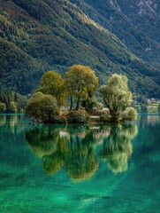 A tranquil island nestled amidst a vibrant lake, reflecting the lush greenery of surrounding mountains.