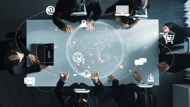 A professional business team collaborates on innovative ideas over a table with digital interfaces, communication symbols, and global connectivity concepts showcased. Raster