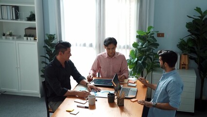 Top view of team working together to brainstorm idea while project manager talking to phone at meeting room. Male leader calling investor and present plan while team discussing strategy. Convocation.