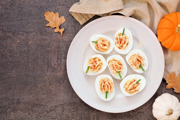 Fall pumpkin theme deviled eggs. Overhead view table scene on a dark background. Autumn breakfast concept.