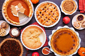 Homemade autumn pie table scene. Top view on a dark wood background. Variety of apple, pumpkin and pecan pies.