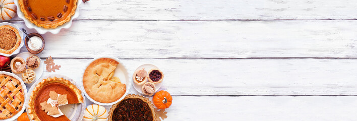 Homemade fall pie corner border. Overhead view on a white wood background with copy space. Variety of apple, pumpkin and pecan pies.