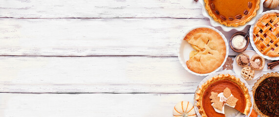 Homemade autumn pie side border. Top down view on a white wood banner background with copy space. Variety of apple, pumpkin and pecan pies.