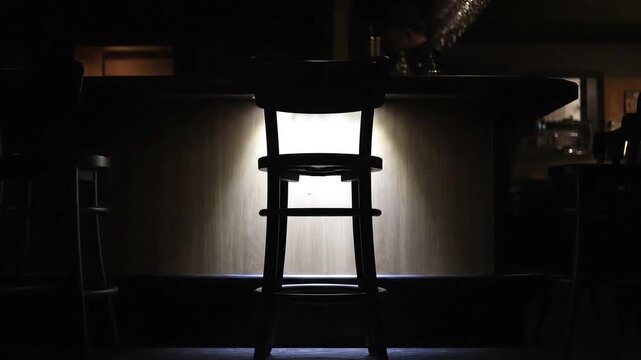 Bar stool silhouette against warm glowing light, inviting ambiance for a relaxing night out