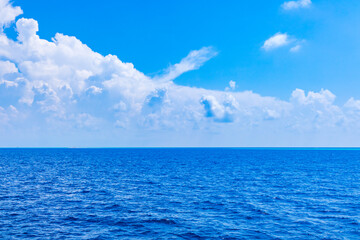 Landscape of beautiful summer sparkling sea water contrasts with bright blue sky and clear white clouds. Space for free texts.