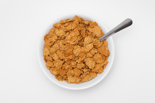 Overhead view of bran flakes cereal in a bowl with a spoon. Healthy breakfast food high in fiber and nutrition, ideal for diet, organic lifestyle, and wholesome morning meals.