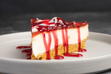 Cheesecake slice with fruit sauce and glaze on ceramic plate over burlap, top view food photography for dessert presentation and culinary design