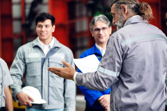 Leaders of a production team planning work on the factory floor. Manager giving a briefing to a group of factory workers.