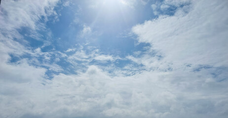 Cumulus white clouds in blue sky background, sun rays, nature photography