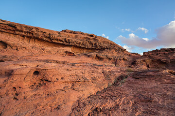 Rocky formations at Wadi Rum desert, only few plants growing over arid terrain, blue sky above