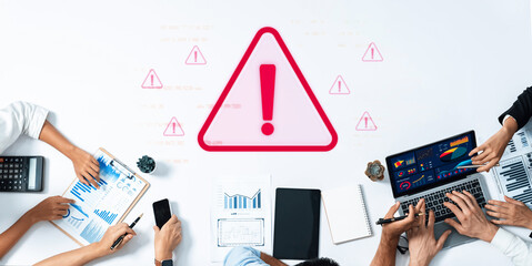 A diverse business team gathers around a table with technology and documents, analyzing data while a prominent warning sign emphasizes the importance of caution in decision-making. Trope