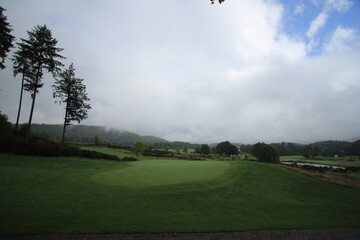 Golf course putting green under cloudy sky