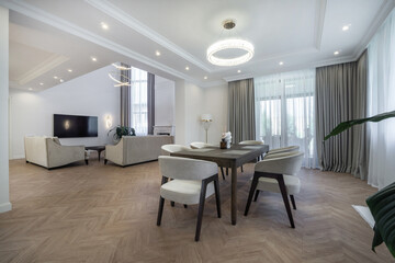This spacious living room features contemporary furniture, large windows, and a stylish design. Natural light enhances the elegant atmosphere, creating a welcoming space for gatherings