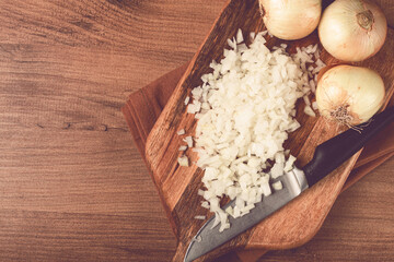 finely chopped onion on a chopping board with a knife, wooden table, top view, no people,