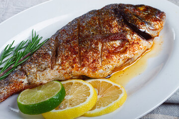 baked dorado fish, in the oven, fried dorado, with spices and herbs, on a white plate, top view, homemade, no people,