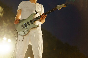 Obraz premium Musician performing on stage with electric guitar during a nighttime concert in an outdoor venue