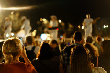 Crowd enjoying a live music performance at night with colorful lights in an outdoor setting