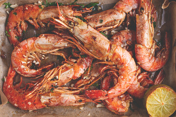 Juicy grilled shrimp, placed on a baking sheet lined with parchment paper, garnished with herbs and lemon.