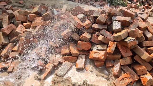 A pile of bricks, construction materials. The bricks are being soaked with water. The bricks are being prepared for masonry.Pile of old red bricks. Beautifull 4k Footage.