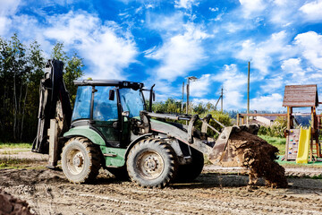 Loader with bucket filled with sand moves on dirt road track, working on construction task. © grigvovan