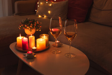 Cozy evening scene with candles, wine glasses and warm lighting.