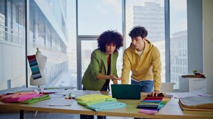 Worried colleagues discussing design project looking laptop at fashion agency.  - Powered by Adobe