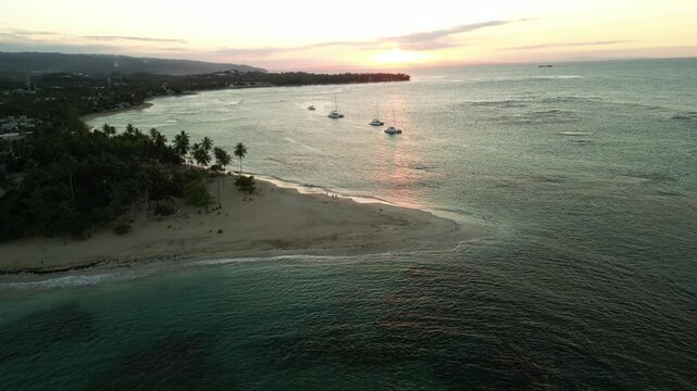 Golden twilight at Punta Popy, Dominican Republic, filmed in stunning 4K from the air. Serene palms, shimmering ocean, and evening catamarans create a peaceful tropical scene for tourism or lifestyle 