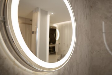 Fototapeta premium Close-up of a circular LED illuminated mirror in a bathroom setting