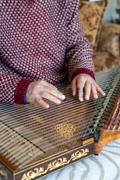 old man playing traditional turkish instrument qanun	
