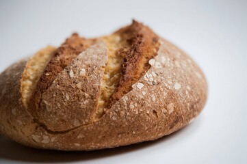 Fototapeta premium Close-up of a whole wheat bread loaf against a plain white backdrop