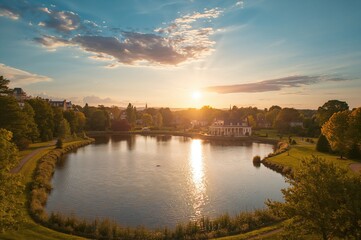 Obraz premium Sunset over a serene lake with a house and summer sky
